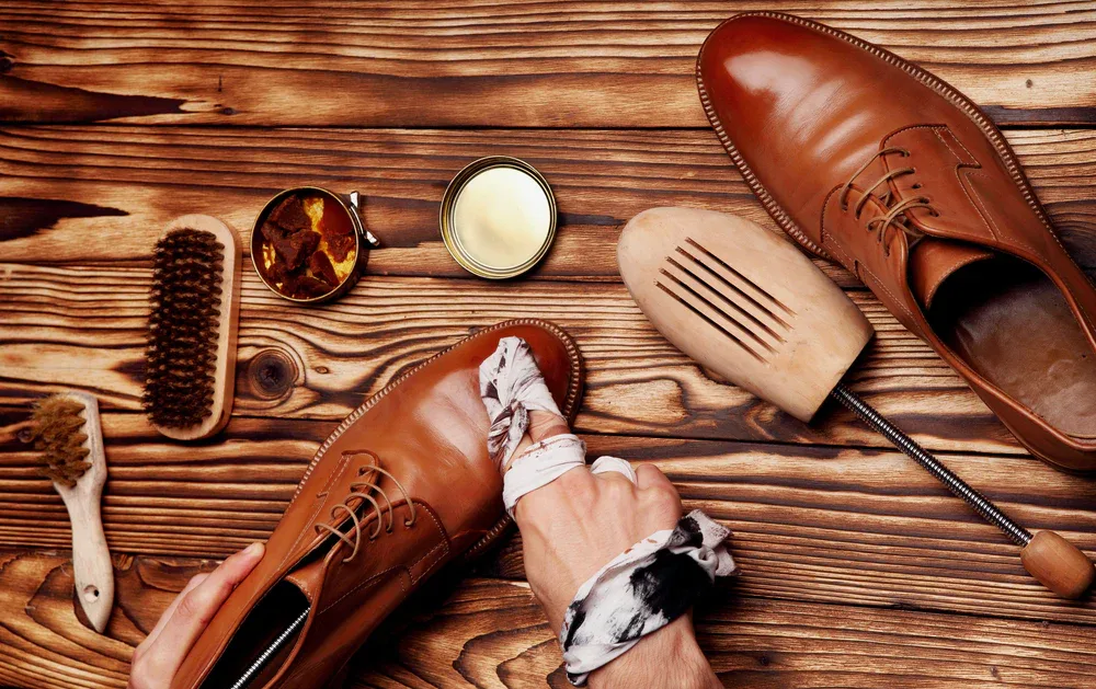 Nécessaire de cirage : brosses, pâtes et chiffons devant une paire de souliers